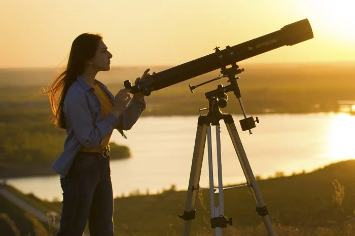 woman with telescope during sunset